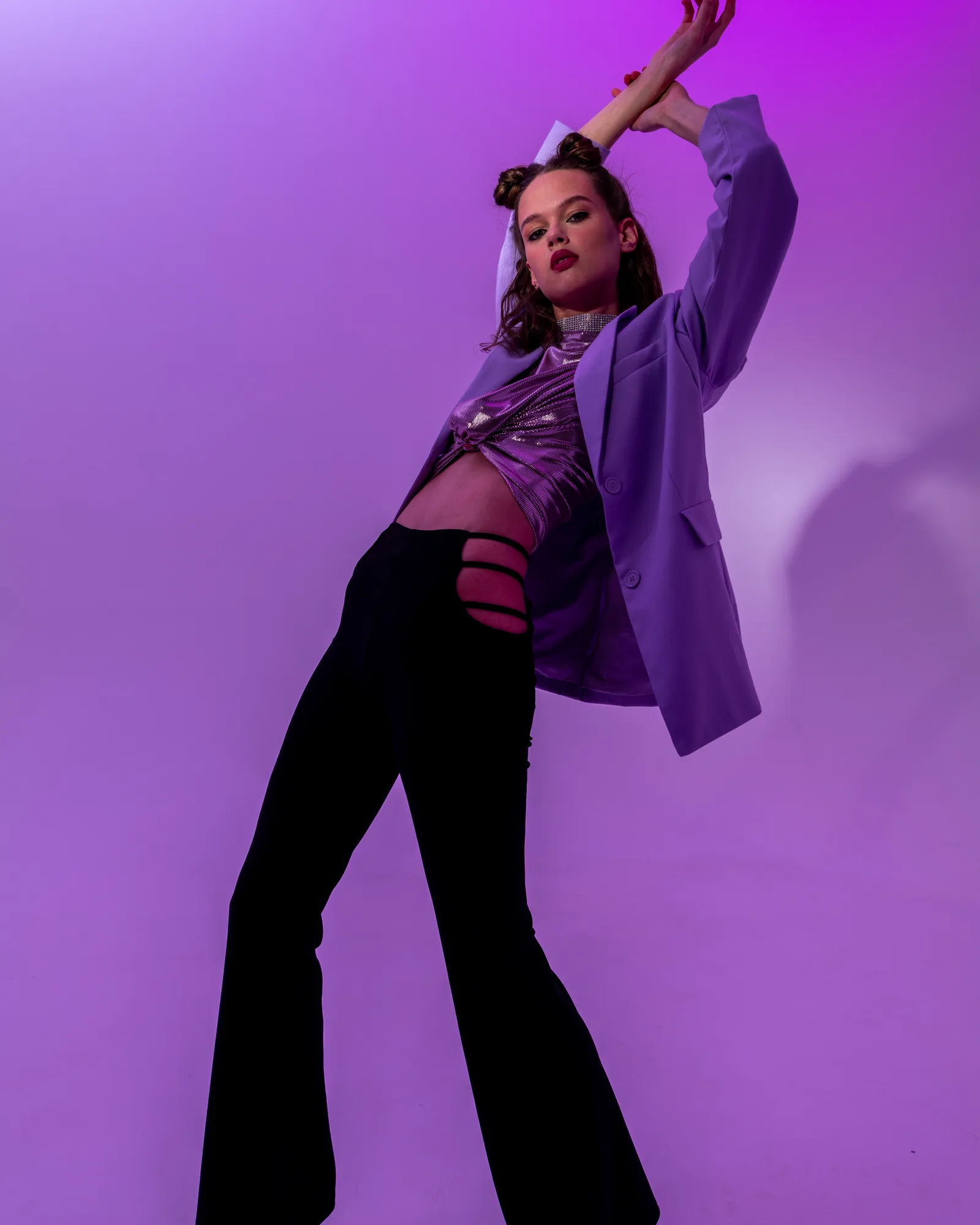 Fashion model photographed against a purple studio background before compositing
